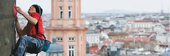 Mann klettert am Flakturm vor Wien-Panorama